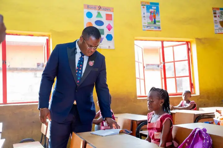 Dr Paddy Iyamu looking at a pupil's reading book in a classroom