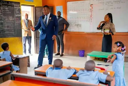 Dr Paddy Iyamu speaking with teachers and pupils in a classroom