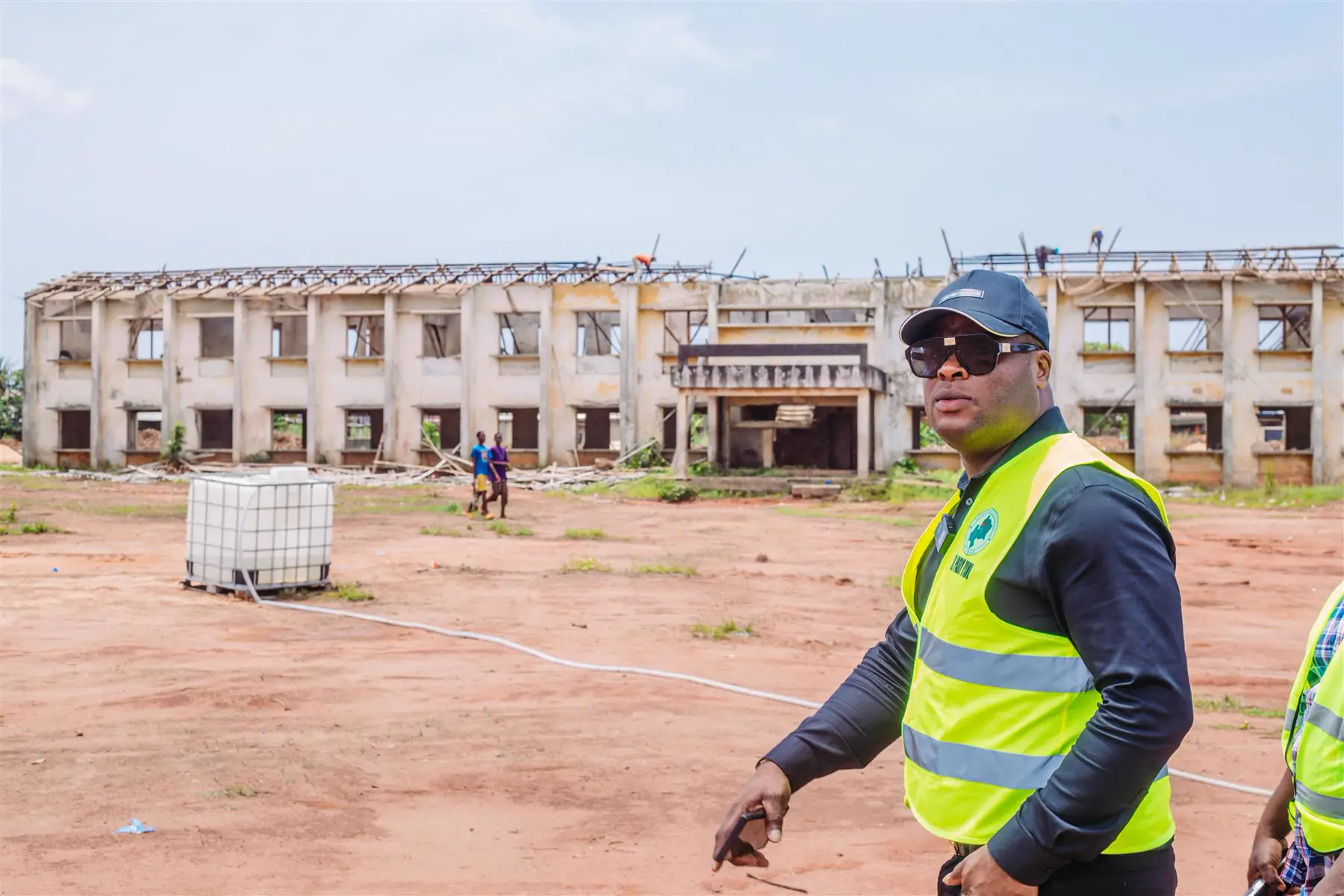 A large school building under reconstruction with Dr Paddy Iyamu inspecting